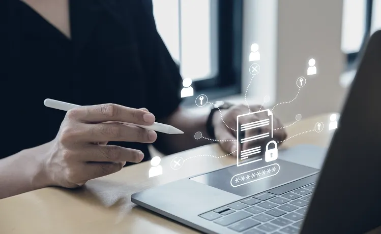 A professional using a laptop with a stylus, featuring holographic icons of secure data and connections, representing Trinergy's commitment to digital data security and innovative solutions.