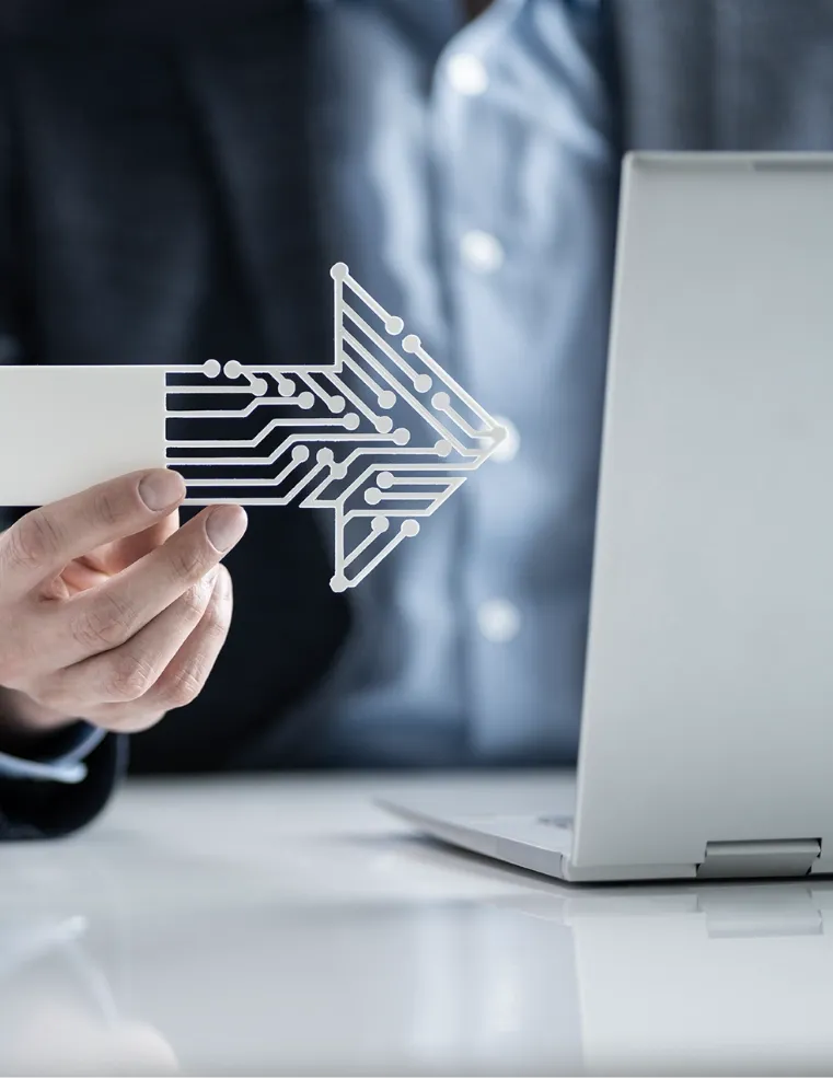 A professional holding a futuristic circuit-like arrow symbol next to a laptop, representing Trinergy's focus on driving digital transformation and technological innovation.