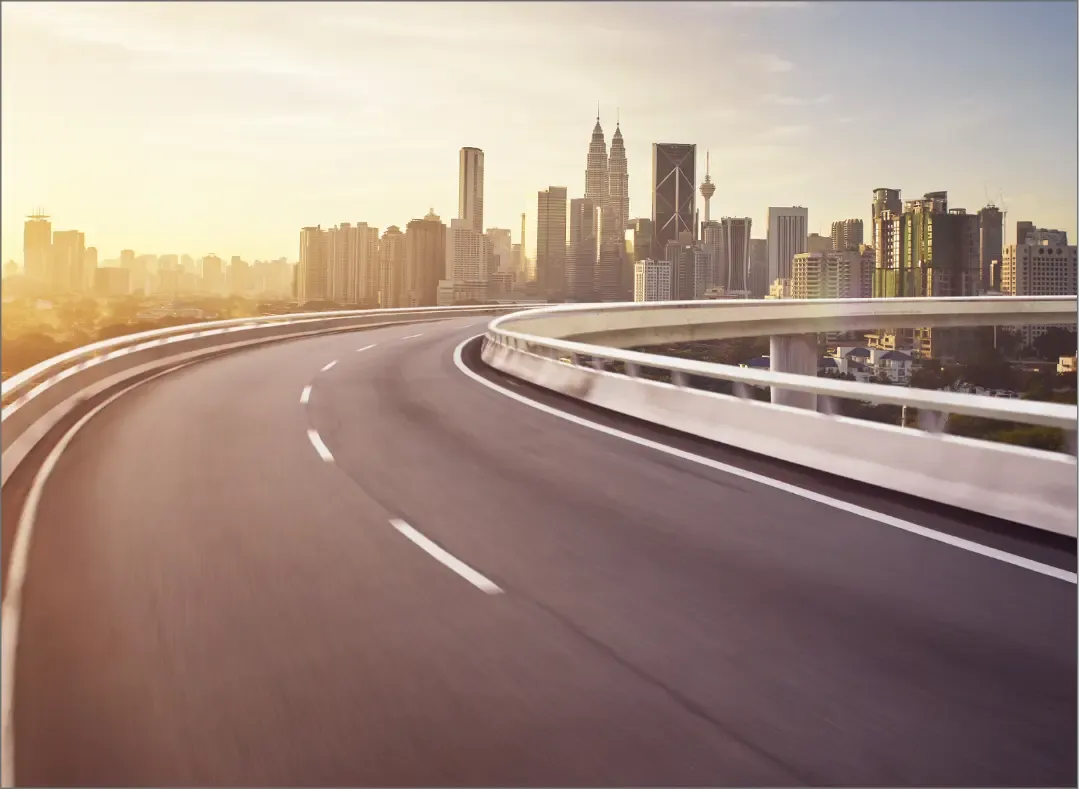 A modern highway leading to a vibrant city skyline at sunrise, symbolizing advanced infrastructure solutions powered by Trinergy.