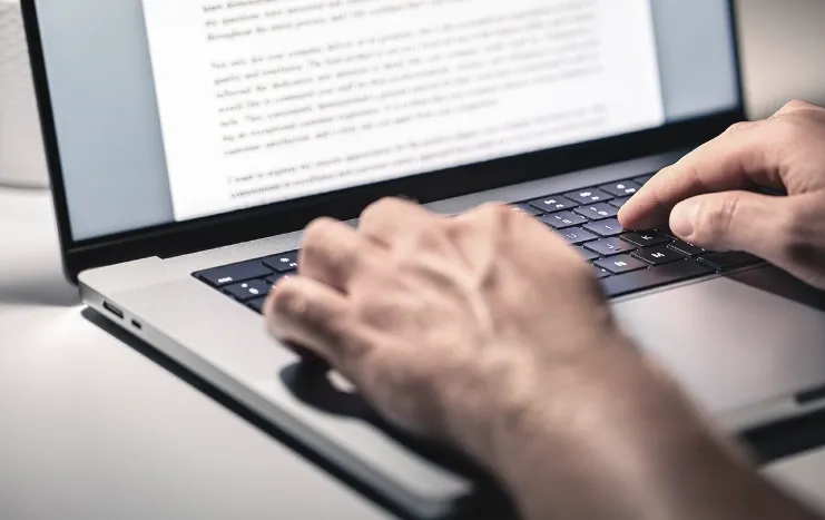 Close-up of hands typing on a laptop keyboard, representing Trinergy's professional content writing and digital document creation services.