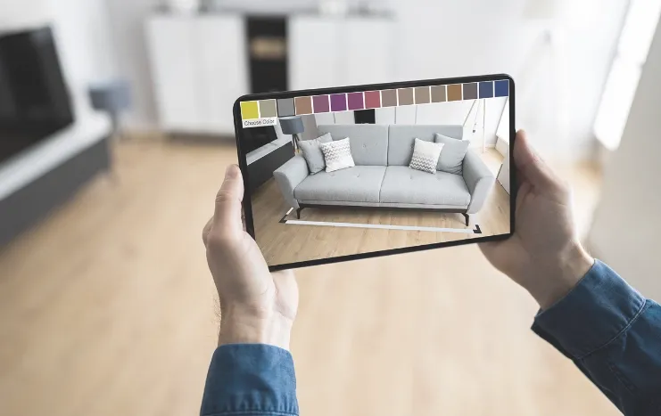 Augmented reality interior design visualization by Trinergy, showcasing a virtual sofa on a tablet screen in a living room setting.