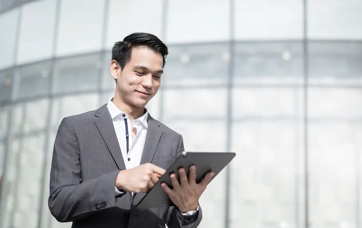 A business professional in a suit using a tablet, representing Trinergy's digital solutions for modern enterprises.