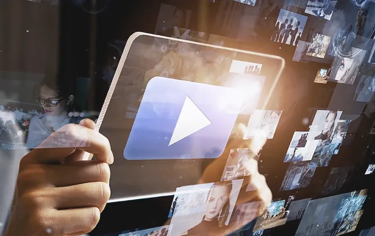 Person holding a digital tablet with a streaming play button, surrounded by video thumbnails, representing Trinergy's digital video streaming solutions.