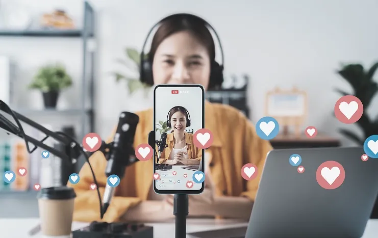 Content creator live streaming in front of a smartphone, with heart and like icons, showcasing Trinergy's live streaming and content creation solutions.