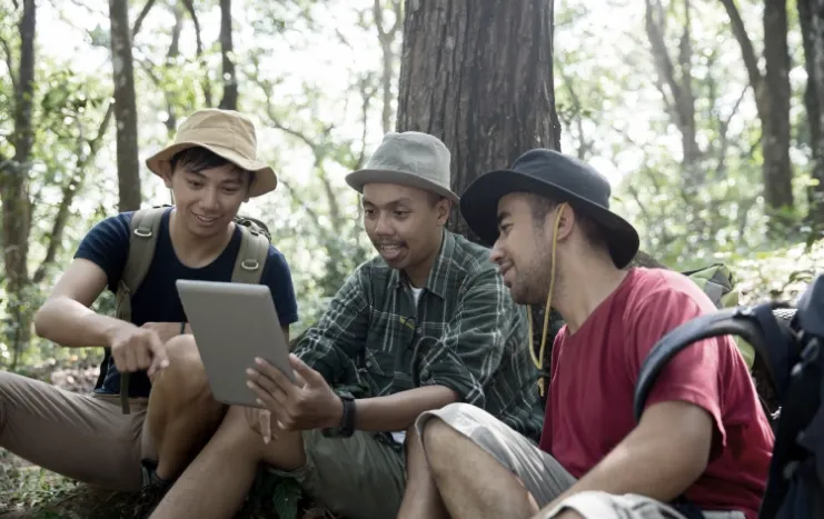 Trinergy enabling digital connectivity as a group of hikers use a tablet in a forest setting.