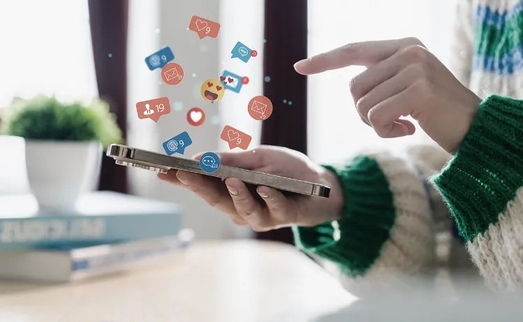 A person interacting with a smartphone, with floating social media icons representing likes, shares, and comments, showcasing Trinergy's focus on social media engagement and digital marketing solutions.