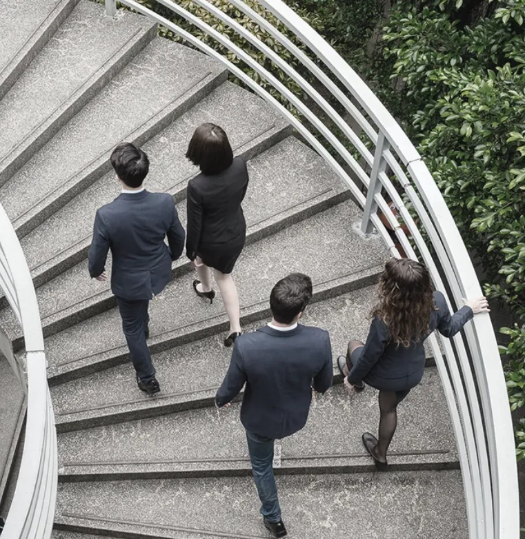 Trinergy team ascending a spiral staircase, symbolizing the journey of continuous improvements in business operations.