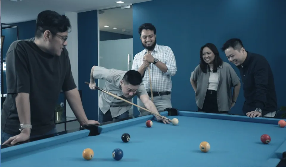 Trinergy team bonding through a game of pool, highlighting the importance of relaxation and team connection.